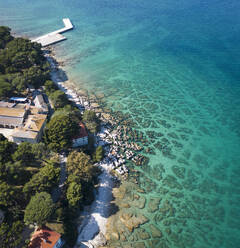Luftaufnahme des kristallklaren Wassers entlang der Küstenlinie mit felsigem Meeresboden auf der Insel Veliki Brijun, Nationalpark Brijuni, Istrien, Kroatien. - AAEF24500