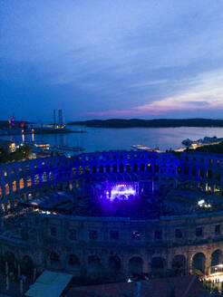 Luftaufnahme der Arena des Amphitheaters von Pula während eines Konzerts bei Sonnenuntergang, einem römischen Amphitheater mit unterirdischem Museum in der Innenstadt von Pula, Istrien, Kroatien. - AAEF24559