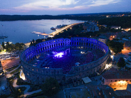 Luftaufnahme der Arena des Amphitheaters von Pula während eines Konzerts bei Sonnenuntergang, einem römischen Amphitheater mit unterirdischem Museum in der Innenstadt von Pula, Istrien, Kroatien. - AAEF24561