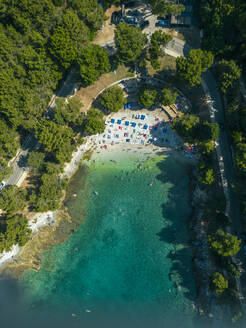 Luftaufnahme von Menschen, die sich am Strand von Gortanova entspannen, einer schmalen Bucht mit türkisfarbenem Wasser, Pula, Istrien, Kroatien. - AAEF24573