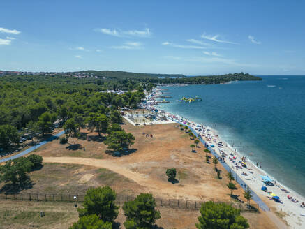 Aerial view of people on the beach relaxing at Hidrobaza park along the coastline near Pula, Istria, Croatia. - AAEF24588