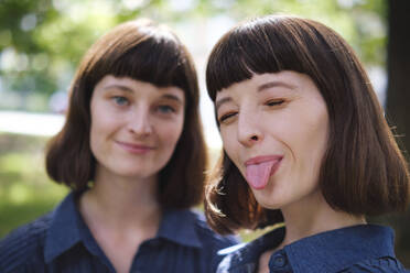 Smiling woman with sister sticking out tongue - ASGF04766