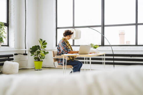 Junger Grafikdesigner arbeitet am Laptop am Schreibtisch im Büro - MDOF01611