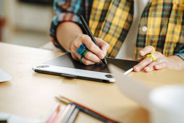 Young illustrator using graphic tablet at desk in office - MDOF01614