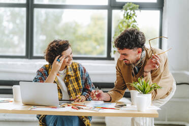 Young graphic designer discussing with colleague at office - MDOF01619