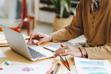 Young illustrator working on laptop at desk in office - MDOF01620