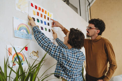 Design-Illustratoren kleben Farbmuster an die Wand im Büro - MDOF01662