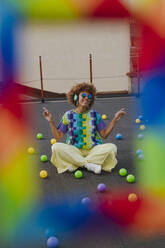 Carefree woman dancing amidst colorful balls on terrace - YTF01422