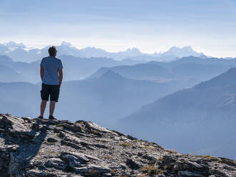 Man standing in front of mountains on sunny day - LAF02834