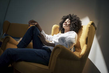 Geschäftsfrau mit geschlossenen Augen sitzt auf einem Sessel im Büro - KNSF09951