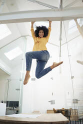 Cheerful businesswoman hanging on iron structure at office - KNSF09957