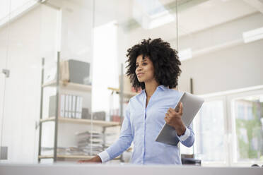 Businesswoman holding laptop at office - KNSF09976