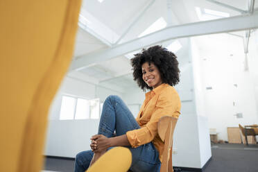 Smiling businesswoman sitting on chair at office - KNSF09980