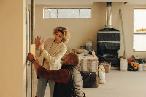 Female architect and a mature male contractor discuss interior renovations in a kitchen. They plan to remodel and upgrade the doors, working together to achieve a modernized and improved home. - JLPSF31033