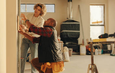 Experienced contractor and an interior designer collaborate on renovating a kitchen. Focused on doorframe and doors, they plan and redesign the house's interior by analyzing a wood sample. - JLPSF31035