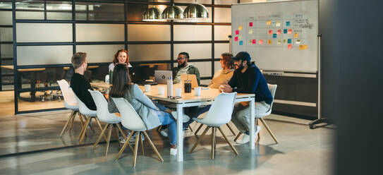 Eine bunt gemischte Gruppe von Fachleuten führt in einem Sitzungssaal eine produktive Diskussion und ein Brainstorming durch. Das Team, das sowohl aus Männern als auch aus Frauen besteht, konzentriert sich auf Projektmanagement und Softwareentwicklung. - JLPSF31115