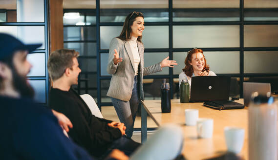 In einem modernen Sitzungssaal führen Fachleute ein Brainstorming durch. Eine selbstbewusste weibliche Führungskraft leitet die Diskussion und fördert Teamarbeit und Kreativität. Die Büroatmosphäre ist professionell und energiegeladen und fördert ein erfolgreiches Tech-Startup. - JLPSF31119