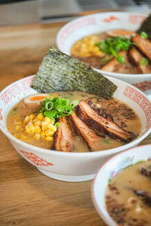 Stockfoto von leckeren Ramen-Suppen mit gekochtem Ei und Fleisch in einem japanischen Restaurant, bereit zum Servieren. - ADSF48857