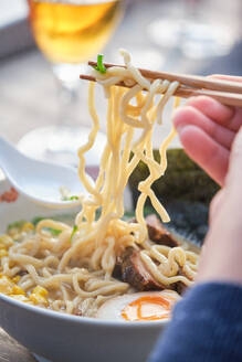 Stockfoto einer unbekannten Person, die eine Nudelsuppe in einem japanischen Restaurant genießt. - ADSF48859