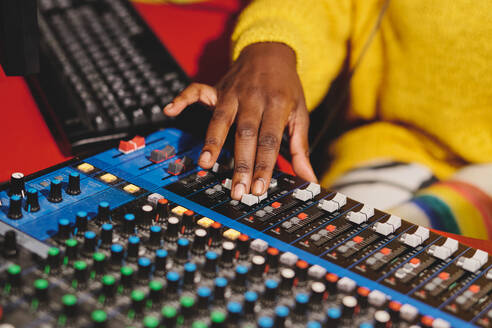 Unrecognizable ethnic female radio host using professional mixing console while working in broadcast studio - ADSF48892