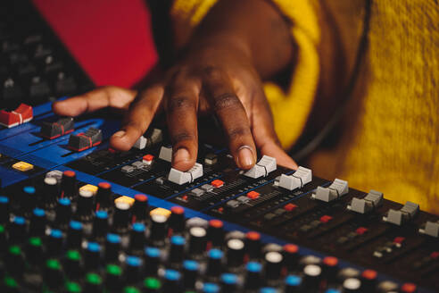 High angle of crop anonymous female sound engineer in yellow sweater working on mixing console - ADSF48898