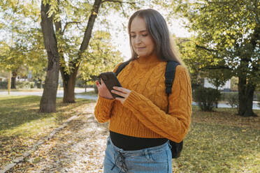 Frau benutzt Smartphone im Herbstpark - OSF02324