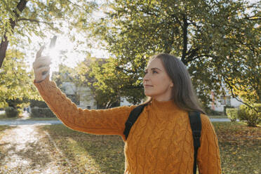 Woman taking selfie through smart phone at autumn park - OSF02325