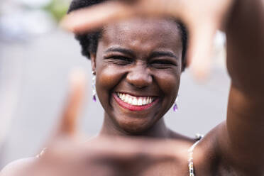 Happy young woman gesturing finger frame - WPEF07799