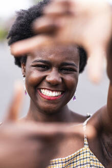 Lächelnde junge Frau gestikuliert Fingerrahmen - WPEF07800