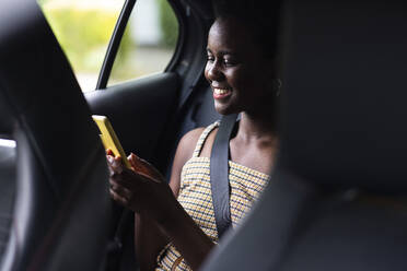 Lächelnde Frau benutzt Mobiltelefon im Auto - WPEF07809