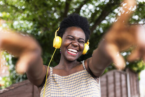 Cheerful woman listening to music through headphones - WPEF07819