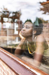 Contemplative woman looking through window - WPEF07823