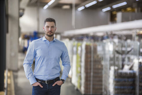 Selbstbewusster Ingenieur, der mit den Händen in den Taschen in der Industrie steht - DIGF20997