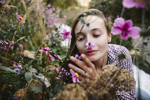Frau riecht an Blumen im Park - EYAF02860