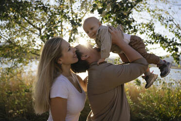 Happy parents playing with son near tree - YBF00305