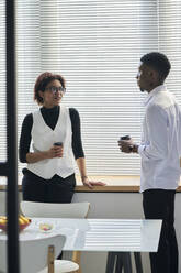 Smiling young businesswoman having discussion with colleague in office - DSHF01069