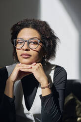 Young businesswoman wearing eyeglasses sitting in office - DSHF01110