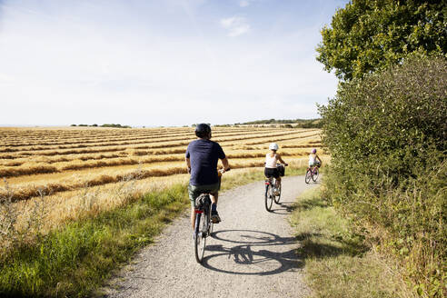 Man and his daughters bicycling on rural road - FOLF12365