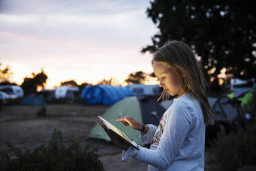 Girl using tablet PC while camping at sunset - FOLF12372