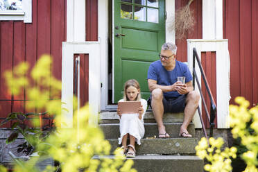 Girl using tablet with his father on doorstep - FOLF12379