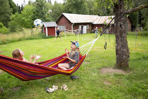 Smiling girls playing with ball in hammock - FOLF12380