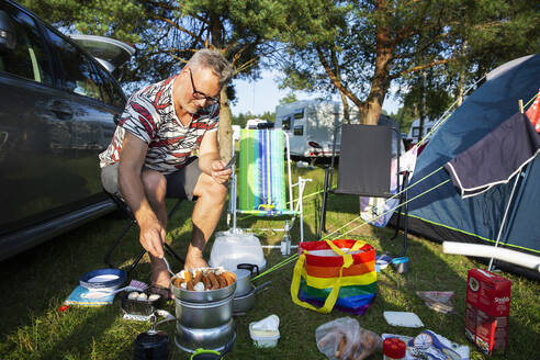 Man cooking sausages while camping - FOLF12382