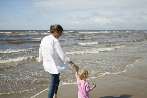 Woman with her daughter walking on beach - FOLF12421