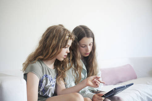 Girls using digital tablet on sofa - FOLF12432