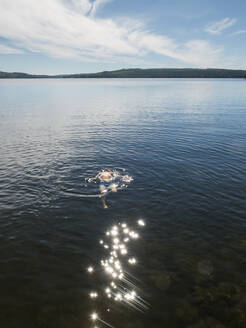 Boy swimming in lake under sunshine - FOLF12437