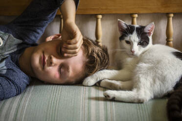 Boy lying on sofa with cat - FOLF12456