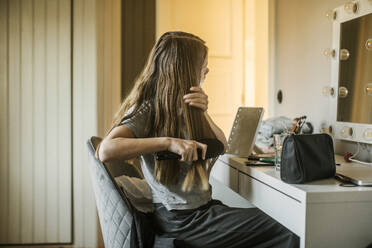 Girl brushing her hair in bedroom - FOLF12471