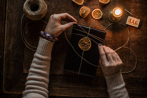 Hands of woman tying dried lemon slice to book - FOLF12479