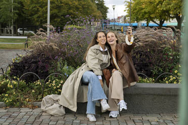 Smiling young women taking selfie in park - FOLF12486