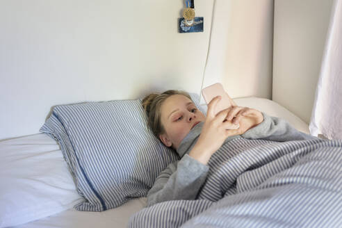 Teenage girl using smartphone in bed - FOLF12508